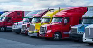 White, red, and yellow trucks in a parking lot